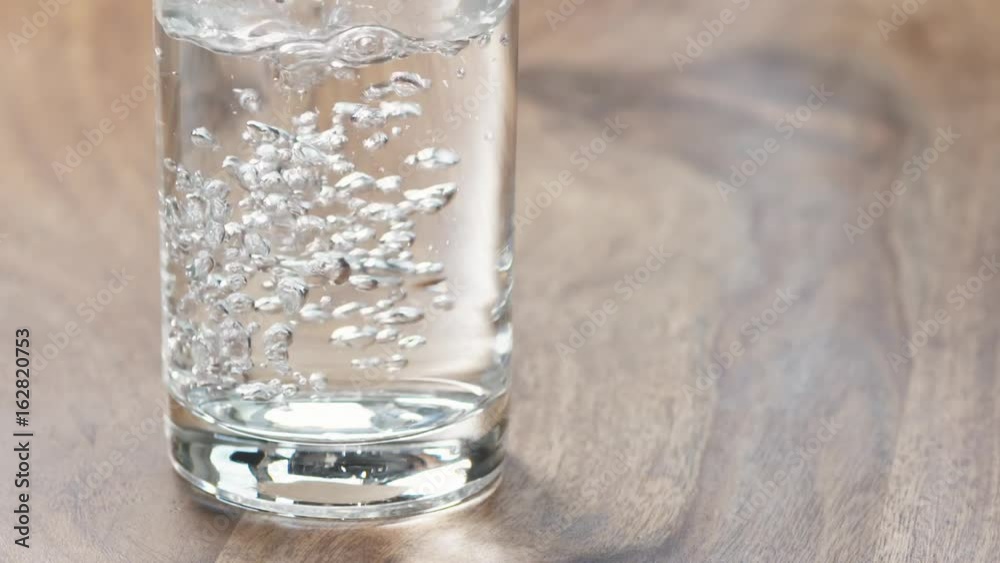 Slow motion of pouring cold water in glass on wood table closeup Slow motion of pouring cold water in glass on wood table closeup