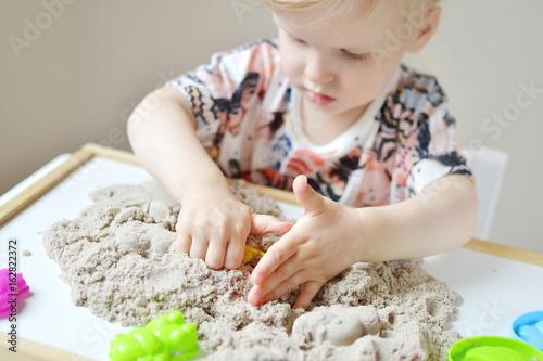 Little girl playing with kinetic sand at home