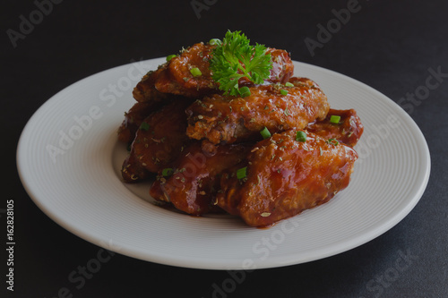 Barbecue chicken wings on white plate served with barbecue dipping sauce. Homemade bbq chicken wing delicious,moist and spicy. Barbecue chicken wing served with chili sauce or tomato sauce(ketchup).