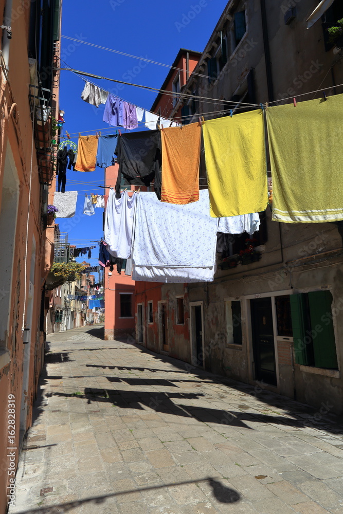 VENICE - APRIL 10, 2017: The view on alley in Venice. Laundry drying in the sun over alley in Venice Italy, on April 10, 2017 in Venice, Italy