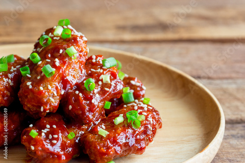 Korean fried chicken wings sprinkled with sesame and spring-onion on wood plate. Homemade Korean barbecue chicken wing delicious,moist and spicy. Fried chicken wings in Korean style on wood table.
