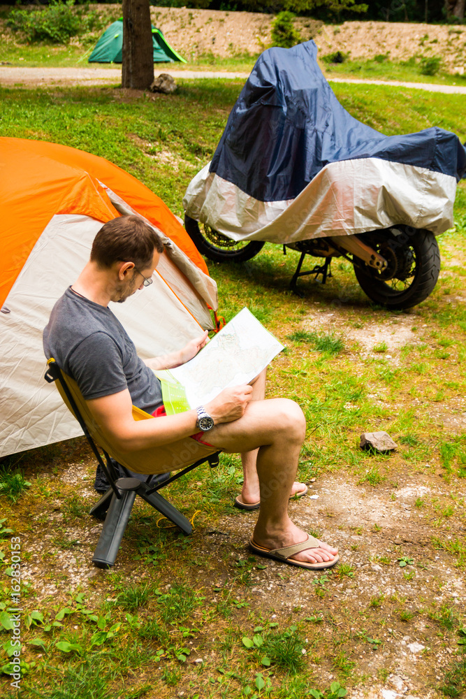Fototapeta premium Man with map next to Camping Tent in nature