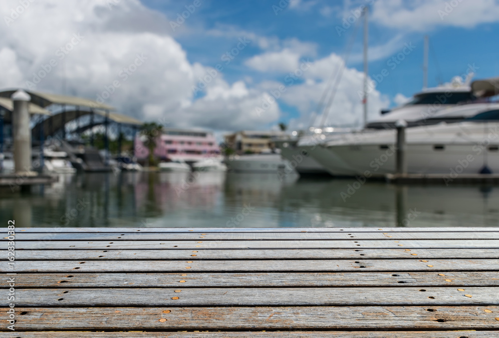 Wooden floor walkway at Marian with blurred boat and yacht background.