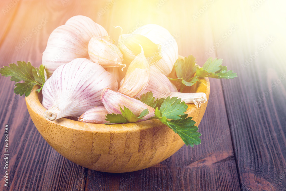 Garlic cloves and garlic bulb in a wooden bowl. Garlic cloves and garlic bulb in a wooden bowl.