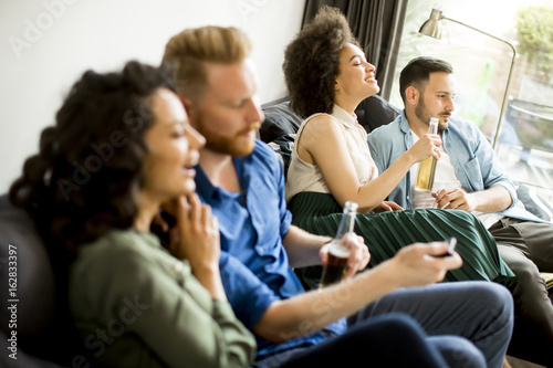 Group of friends watching TV, drinking cider and having fun