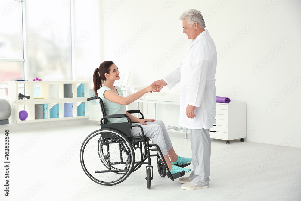 Young disabled woman with senior orthopedist in rehabilitation clinic Young disabled woman with senior orthopedist in rehabilitation clinic