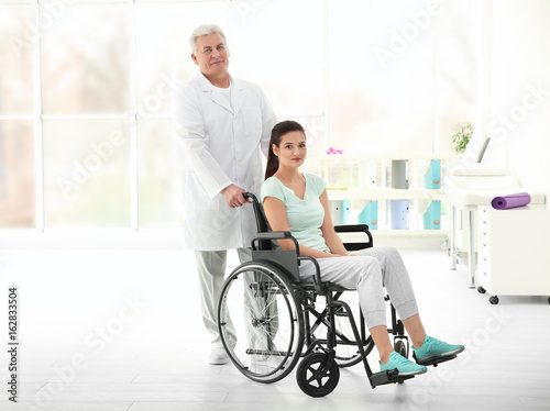 Young disabled woman with senior orthopedist in rehabilitation clinic