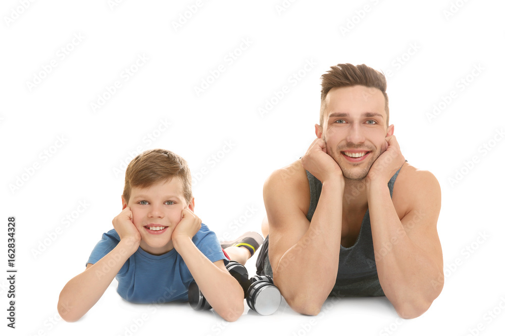 Dad and son with dumbbells lying on white background Dad and son with dumbbells lying on white background