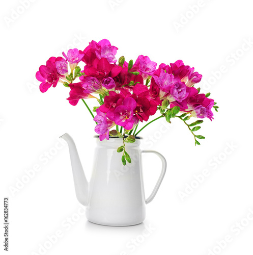 Beautiful bouquet of freesia in watering can on white background
