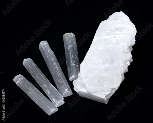 White mexican fish tail selenite with natural selenite rods on black background