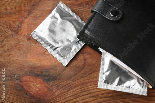 Wallet with condoms on wooden table. Safe sex concept