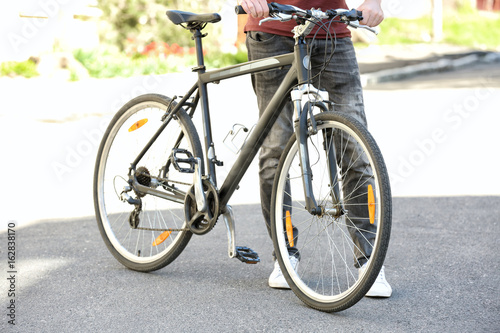 Young man with bicycle outdoors on sunny day