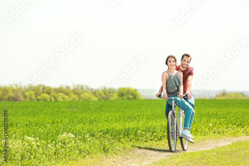 Happy young couple riding bicycle in countryside © Africa Studio