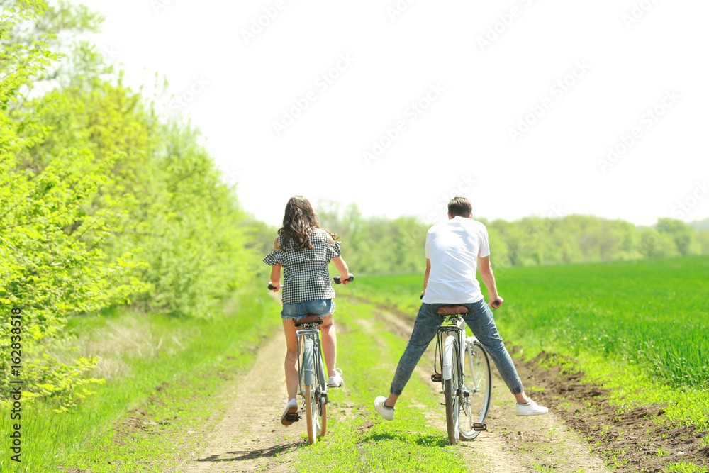 Fototapeta premium Happy young couple riding bicycles in countryside