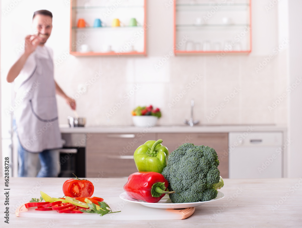 Fresh vegetables on table with man cooking in background Fresh vegetables on table with man cooking in background