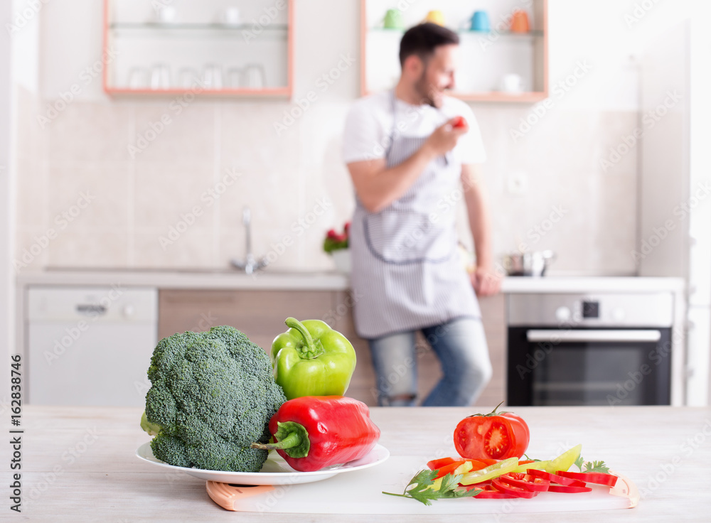 Fresh vegetables on table with man cooking in background Fresh vegetables on table with man cooking in background