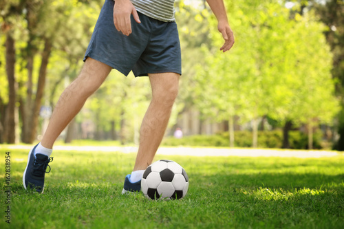 Young man playing football on green grass in park