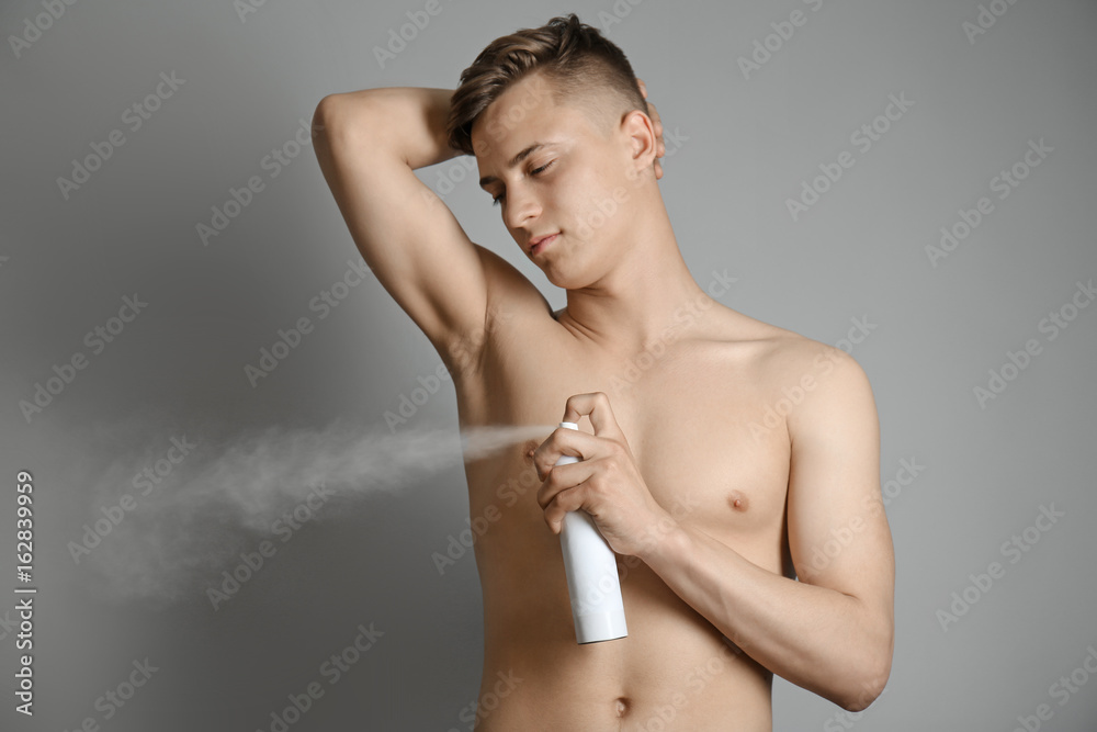 Handsome young man with deodorant on grey background Handsome young man with deodorant on grey background