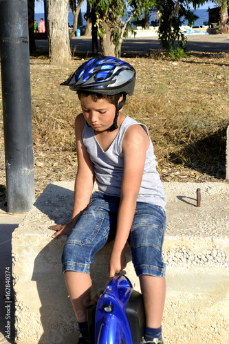 El niño con el casco esta paseando en el parque con la rueda Monowheel..  scooter electrico photo