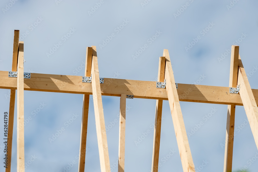 Obraz premium The rafters of the roof of the new wooden house under construction