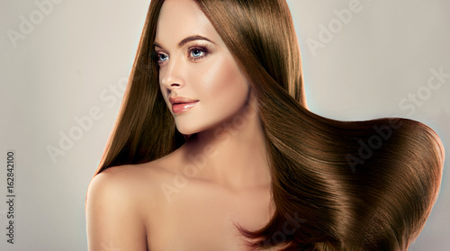 Beautiful brunette girl with long straight smooth hair . A woman with healthy straight hairstyle