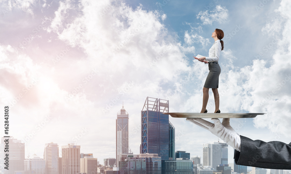 Attractive businesswoman on metal tray with red book in hands against cityscape background