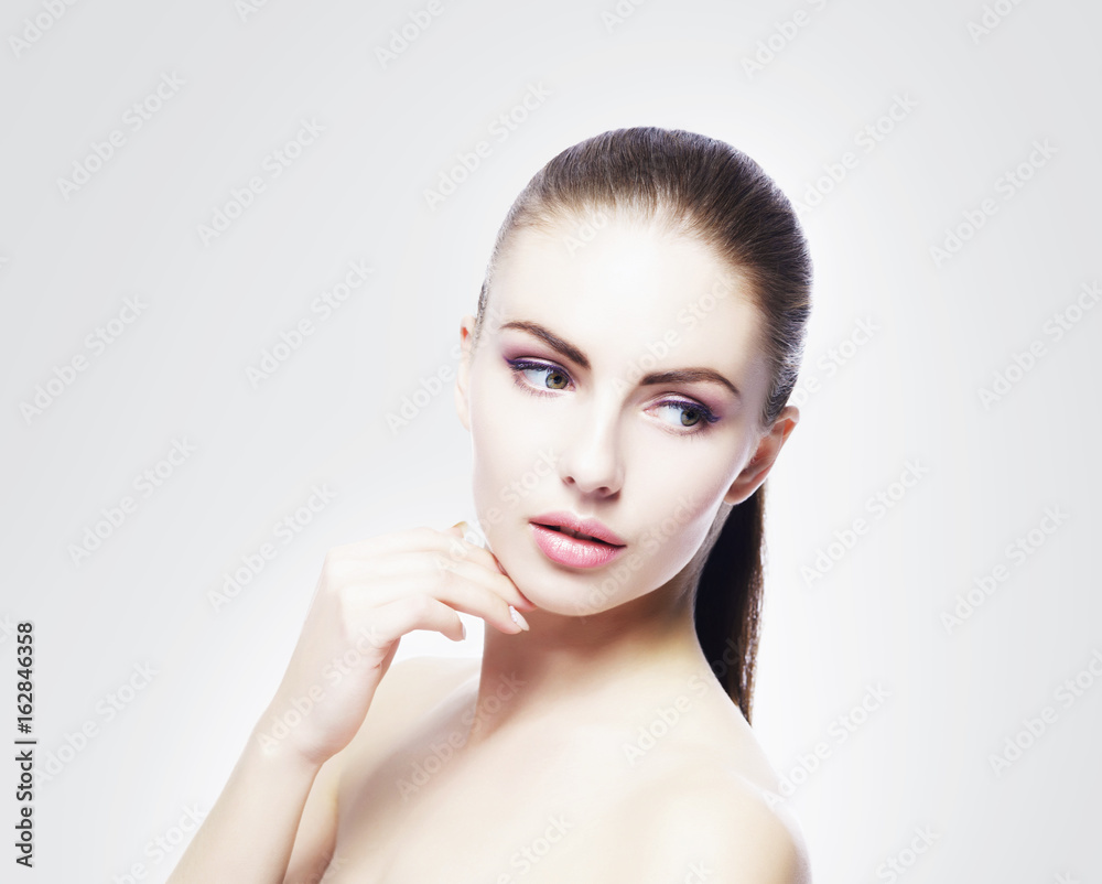 Portrait of young, beautiful and healthy woman: over cold grey background. Healthcare, spa, makeup and face lifting concept.