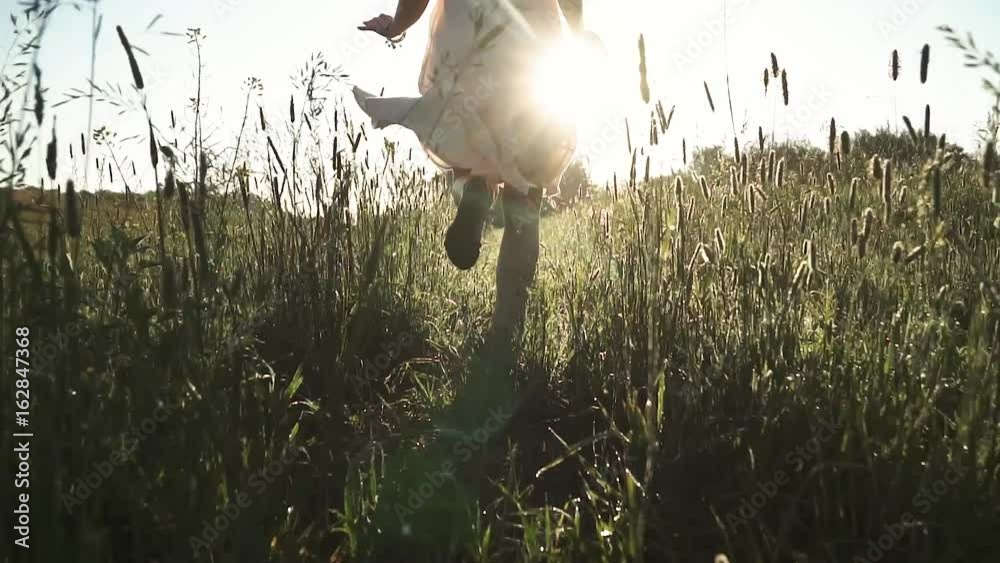 girl hippie runs across the meadow at dawn and sprinkles the dew. slow motion