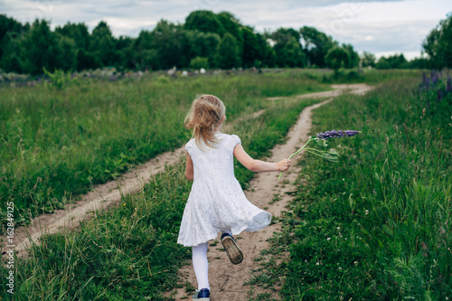 Child runs and jumps on a path in the field