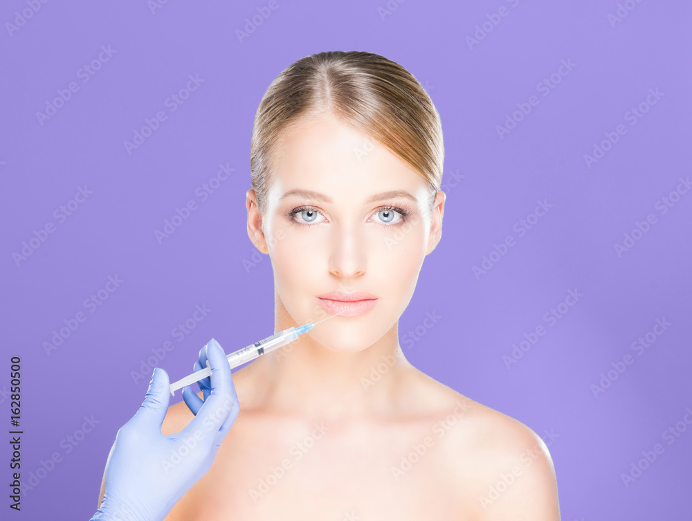 Young and beautiful woman having skin injections over magenta background. Plastic surgery concept. Young and beautiful woman having skin injections over magenta background. Plastic surgery concept.