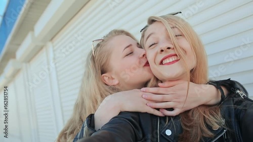 Two young beautiful girlfriends blonde fun and coquettish posing in front of the camera. Do selfie. Spring photo