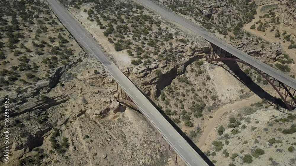 Aerial overhead circle Eagle Canyon Bridge highway desert landscape. Double span interstate I-70 highway crosses deep gorge. Travel traffic overhead drone view. San Rafael Reef.