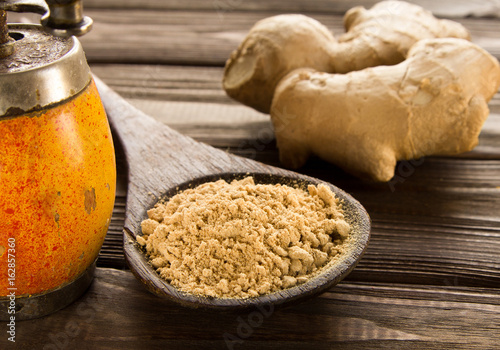 Spice ginger powder,vintage handmill, ginger root  on wooden background. photo