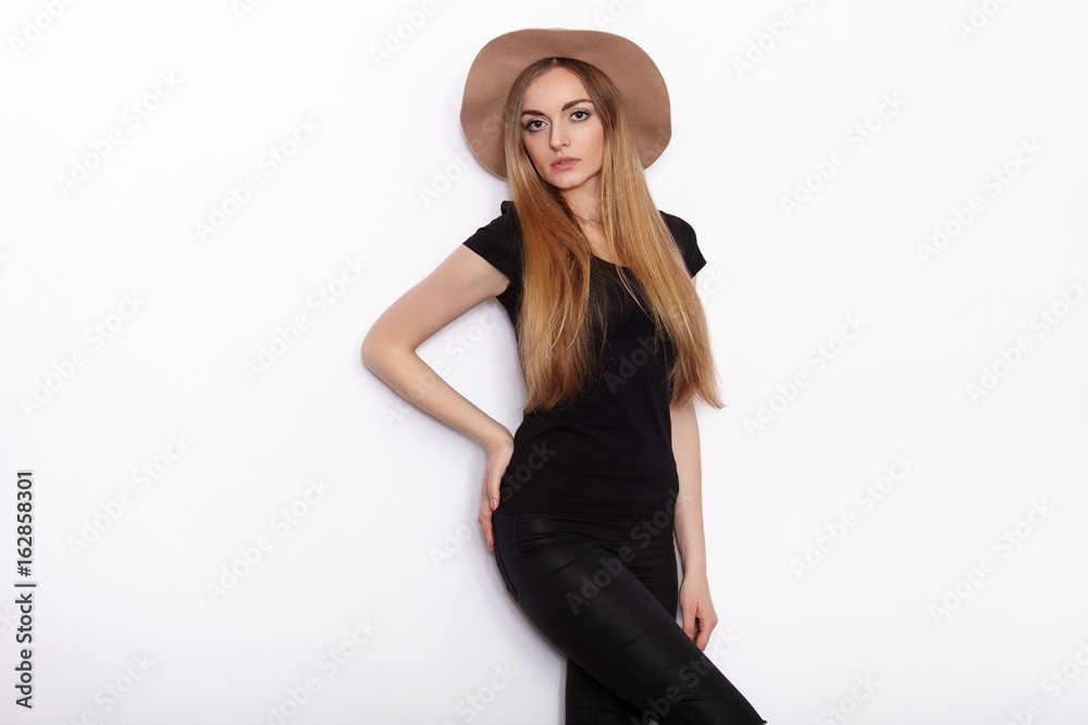 Young beautiful fashion model in women black t-shirt trendy hat posing in studio against white background Young beautiful fashion model in women black t-shirt trendy hat posing in studio against white background