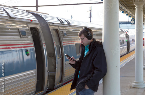 Man listening to music at train station photo