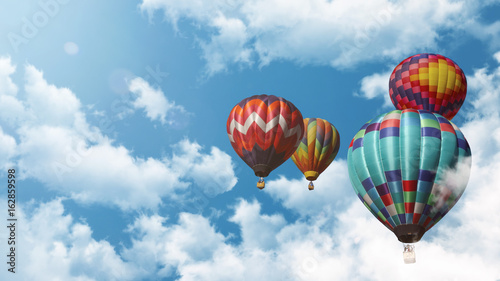 Mehrere Heißluftballons fliegen vor einem blauen bewölkten Himmel bei Sonnenuntergang photo