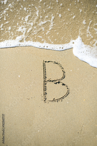 B Letter drawn on the sand beach © photostocklight