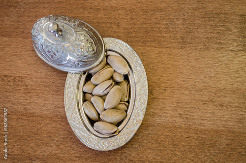 Copper bowl on a wooden table with pistachio