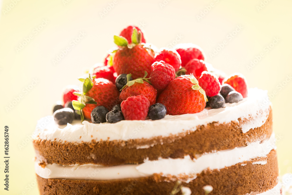 Close up of a homemade wedding cake topped with raspberries, strawberries, and blueberries. Close up of a homemade wedding cake topped with raspberries, strawberries, and blueberries.