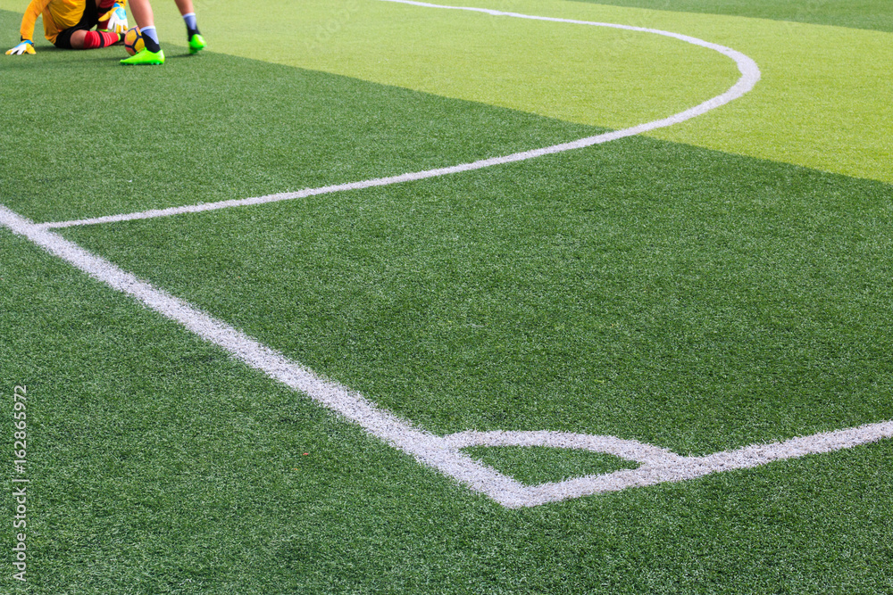 Photo of a green synthetic grass sports field with white line shot from above.