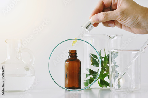 Obraz na płótnie Cosmetic brown bottle containers and scientific glassware, Focus on oil dropping in blank label package for branding mock-up, Research and develop beauty skincare product concept. w salonie