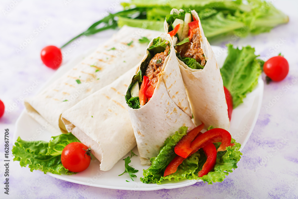 Burritos wraps with minced beef and vegetables on a light background. Burritos wraps with minced beef and vegetables on a light background.
