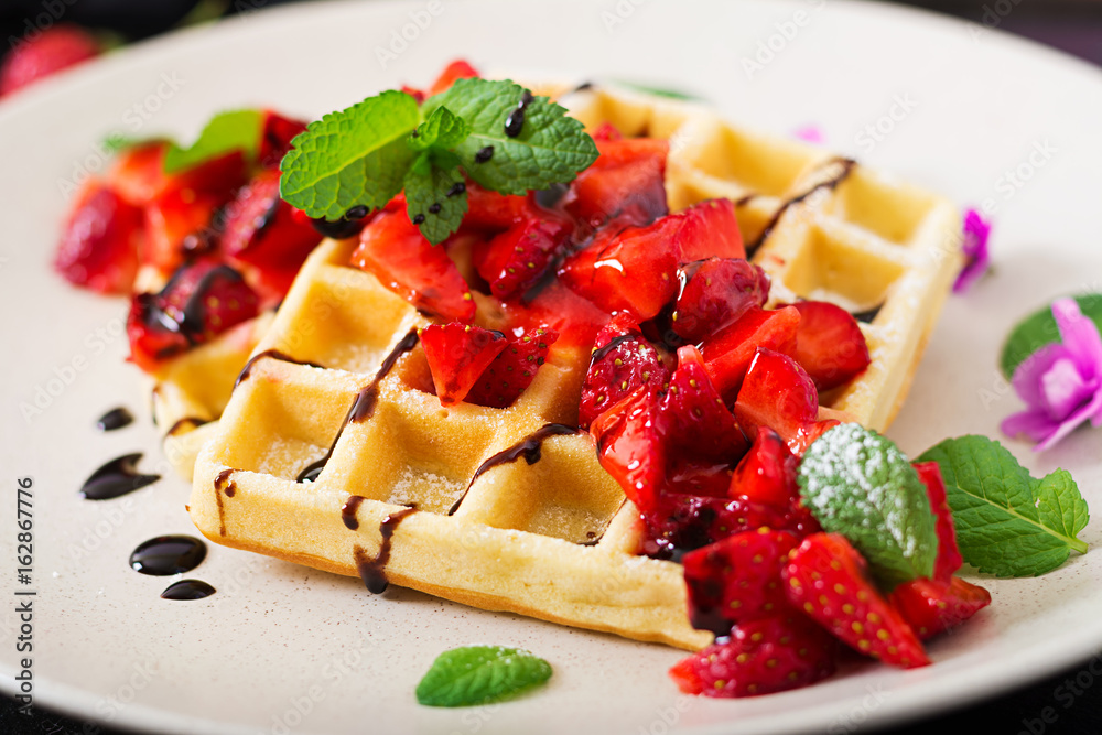 Belgium wafers with strawberries, chocolate and syrup on a plate. Belgium wafers with strawberries, chocolate and syrup on a plate.