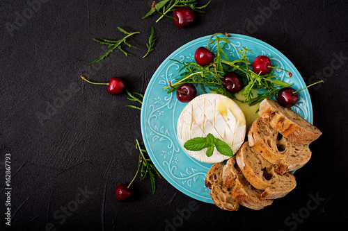 Baked Camembert cheese, toast and arugula salad with  sweet cherries. Flat lay. Top view