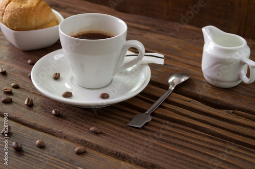 Morning coffee in a cup on a table with croissants and milk