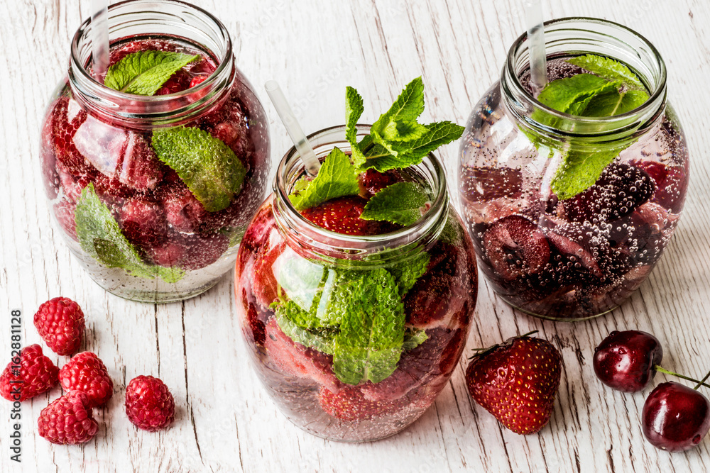 detox water with raspberry, strawberry, cherry on white wooden background. Healthy drinks detox water with raspberry, strawberry, cherry on white wooden background. Healthy drinks