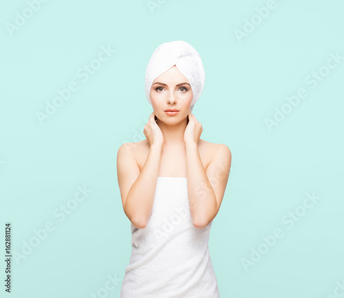 Young, beautiful and natural woman wrapped in towel over cyan background.