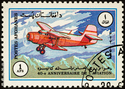 Old aircraft over mountains on postage stamp photo