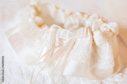 Bride's garter. Bride's traditional symbolic accessory. Beige lace with ribbons and rhinestones.