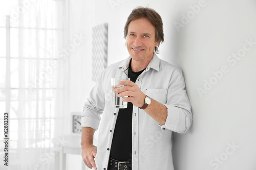 Mature man holding glass of...